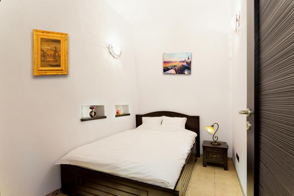 シビウにあるSelect Studioのベッドルーム1室(白いシーツと壁に絵画が飾られたベッド1台付)
