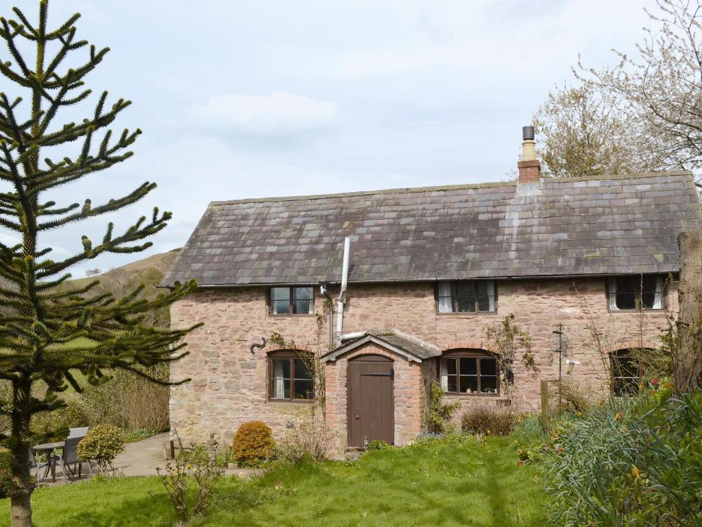 an old brick house with a brown door at Titchbourne Cottage in Clee Saint Margaret