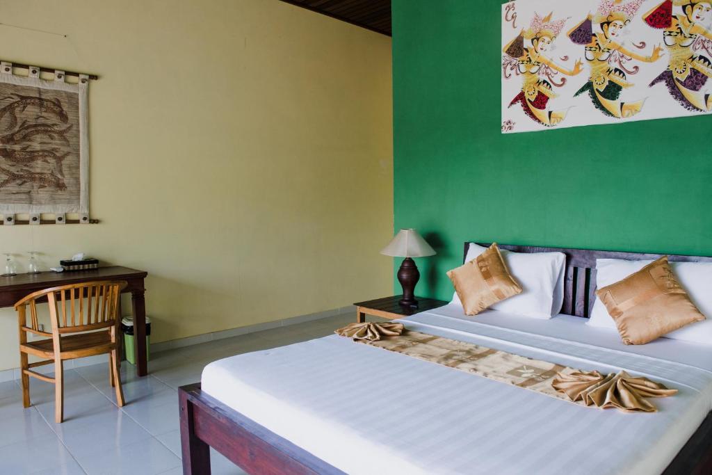 a bedroom with two beds and a table and a desk at Segara Tegeh Tulamben in Tulamben