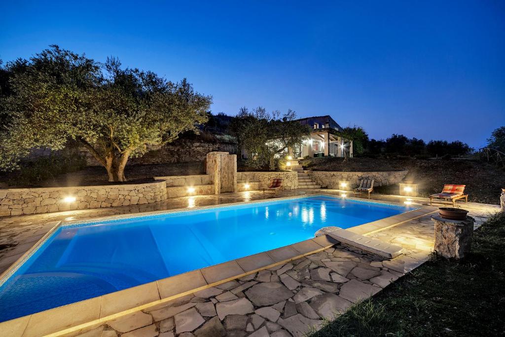 a swimming pool in a backyard at night at Villa Margi in Giarratana