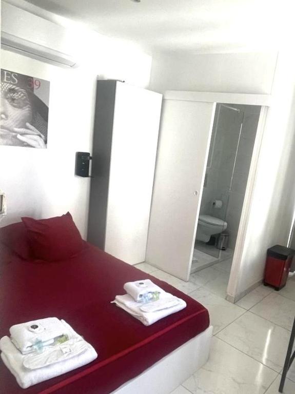 a bedroom with a red bed with two towels on it at Sweet Home Marceau - 6 studios hyper centre proche de la mer et du palais in Cannes