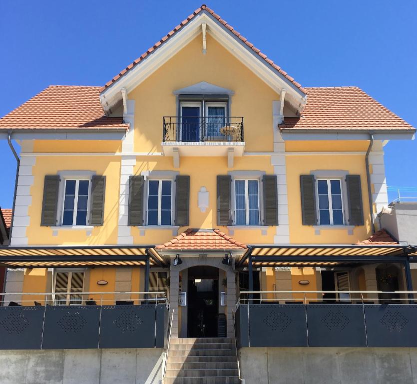 a yellow house with a staircase in front of it at Hotel Restaurant Jura in Kerzers