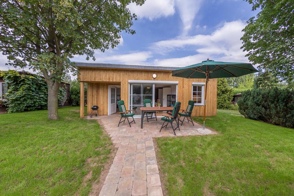 ein Haus mit einem Tisch, Stühlen und einem Sonnenschirm in der Unterkunft Campingplatz am Hünstein in Nohra