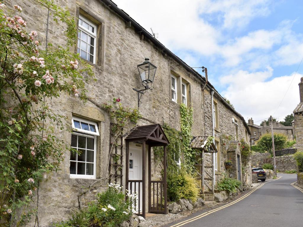 a stone house with a white door on a street at Rose Cottage - Uk34067 in Grassington