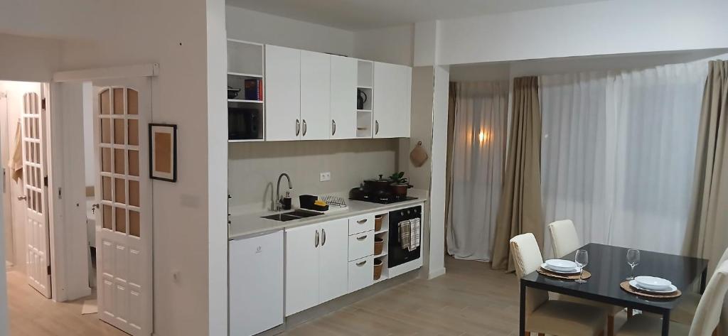 a kitchen with white cabinets and a table and a dining room at Avenida Dr Baltazar Lopes da Silva 33A in Mindelo