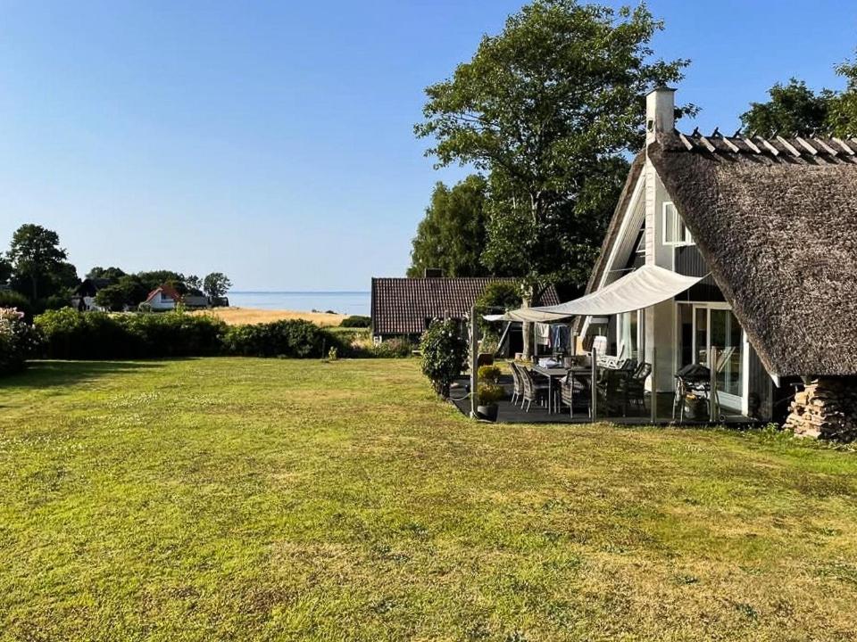 a house with a thatched roof and a grass yard at Charming House With A View Of The Sea in Båring