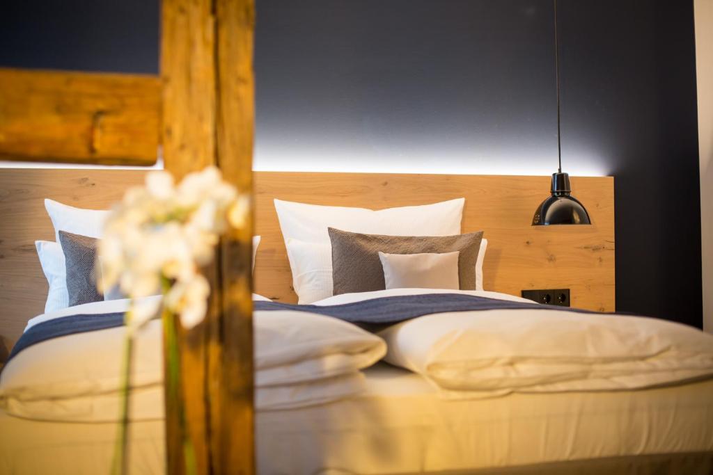 Schlafzimmer mit einem Bett mit weißer Bettwäsche und Kissen in der Unterkunft Bischoffs Hotel in Bad Urach