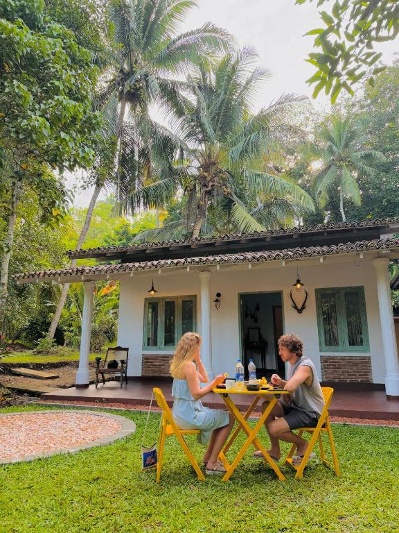 two women sitting at a table in front of a house at LEONS Stay in Galle