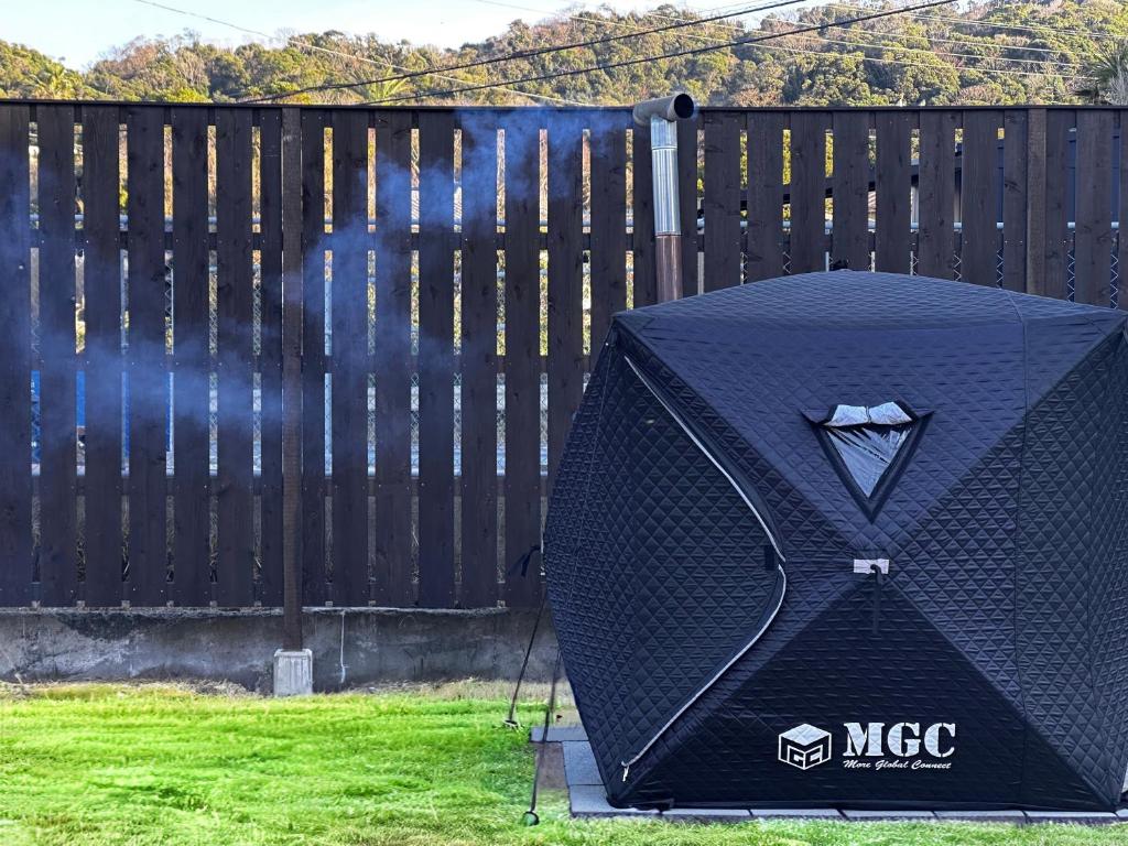 a black grill sitting in the grass next to a fence at Little Seagull by SANA in Tateyama