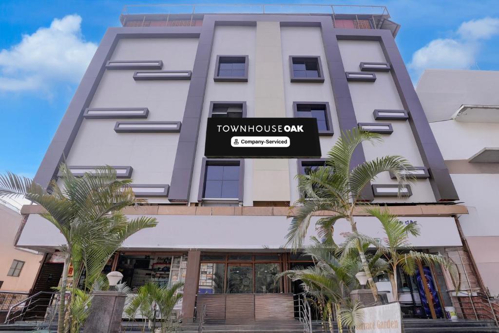 a tall white building with a sign on it at Super Townhouse Oak Dharwad New Bus Terminal Formerly Hotel Aditya Inn in Dhārwād