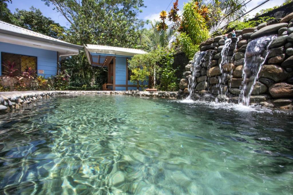 a pool with a waterfall in a backyard with a house at Hotel Casa del Arbol Manuel Antonio - Adults Only in Manuel Antonio