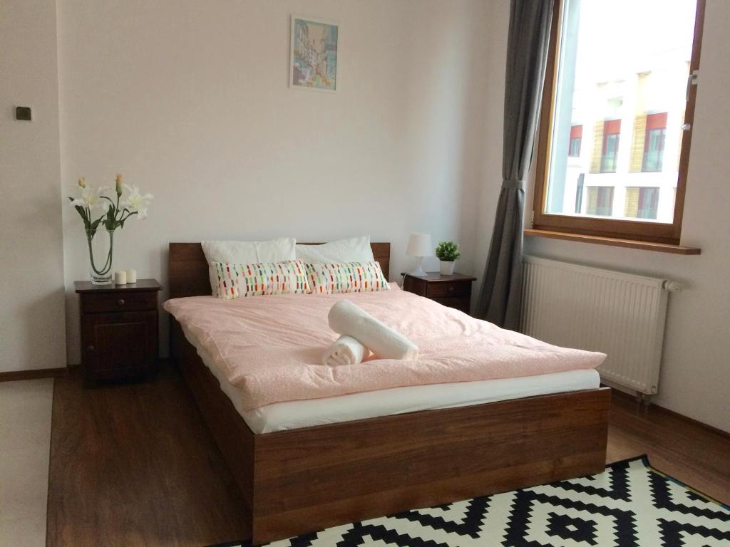 Schlafzimmer mit einem Bett mit rosa Bettwäsche und einem Fenster in der Unterkunft Luxury apartment Piękna in Warschau