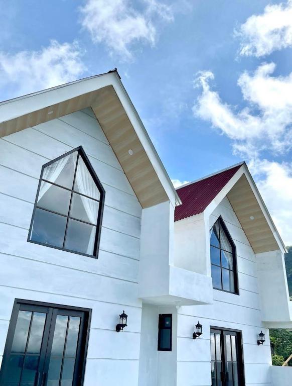a white house with a red roof and windows at Lovia Villa Dieng in Kejajar