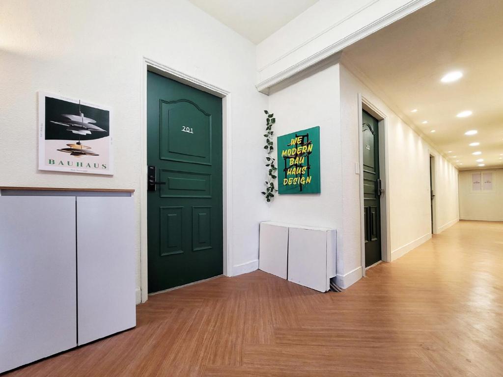 a hallway with a green door and white walls at 부천역 감성 숙소 in Samgong