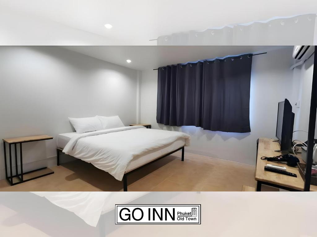a bedroom with a bed and a tv in a room at xx GO INN Phuket Old Town in Phuket