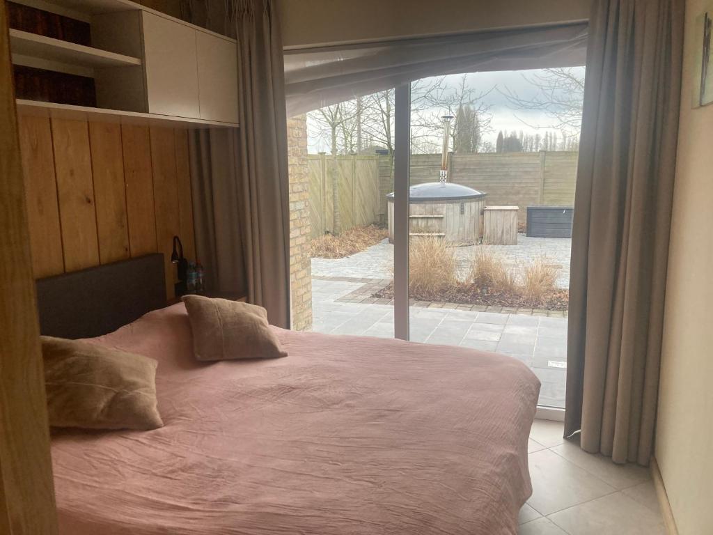 a bedroom with a bed in front of a window at De Notelaar in Alveringem