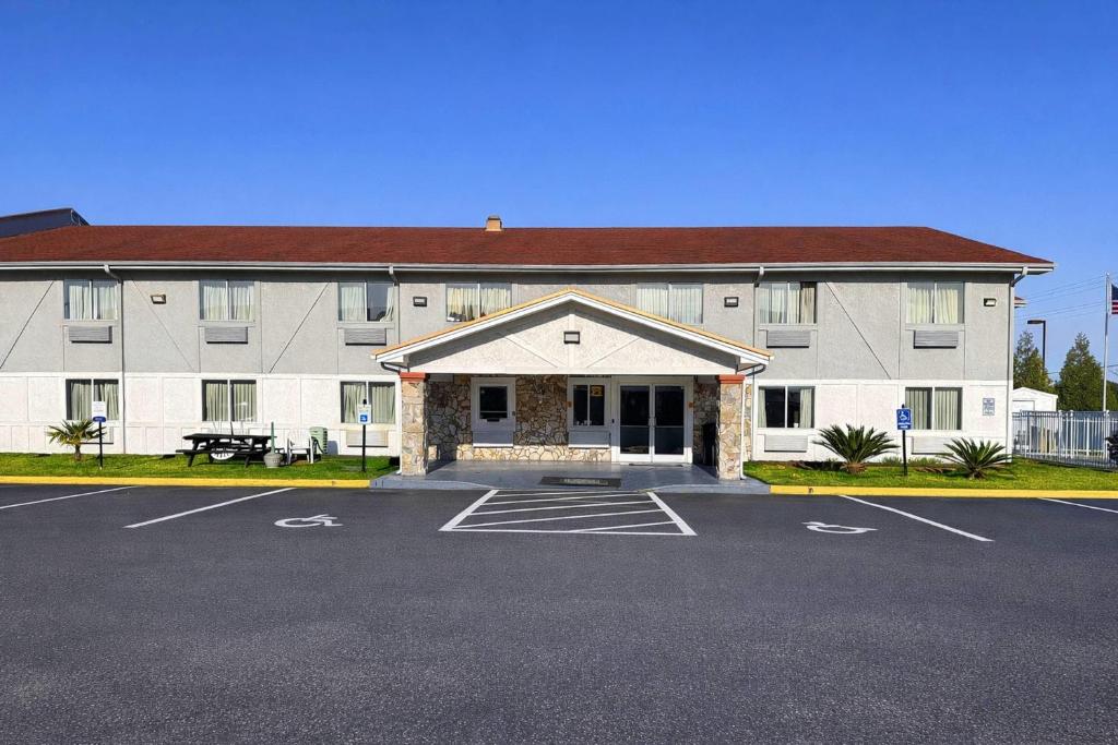 a large building with a parking lot in front of it at Rodeway Inn & Suites Jacksonville near Camp Lejeune in Jacksonville