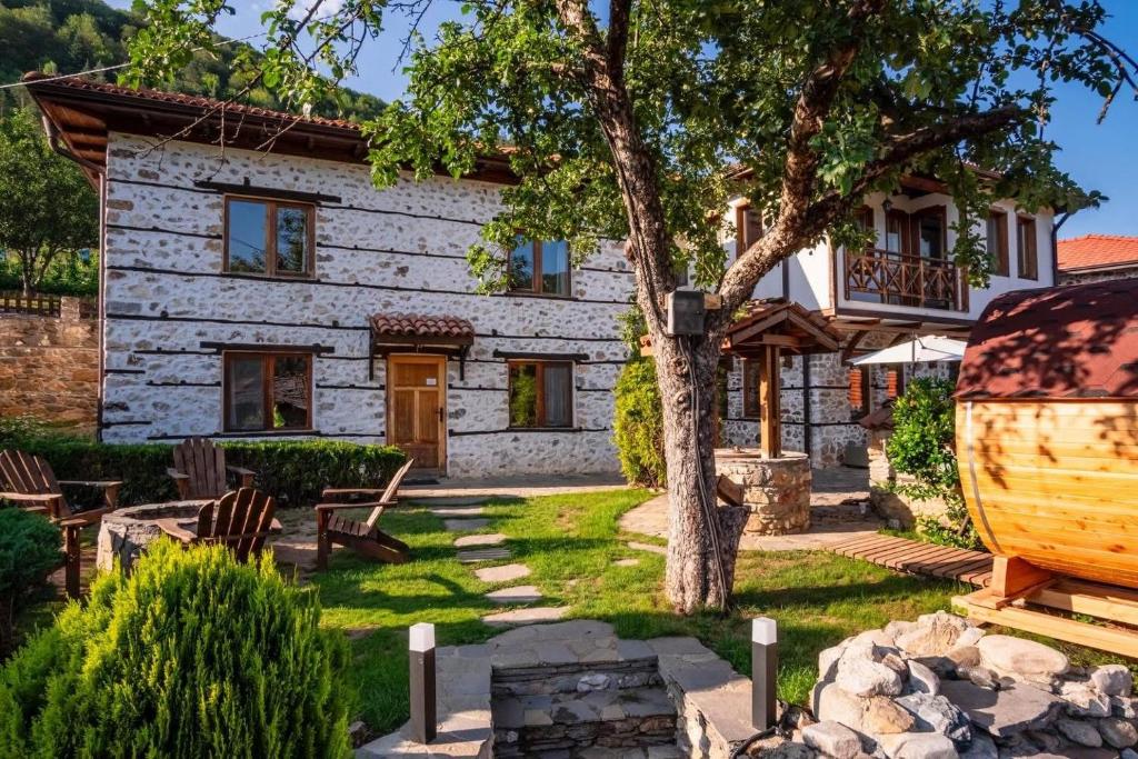 a stone cottage with a tree and a house at Villa Martina in Smilyan