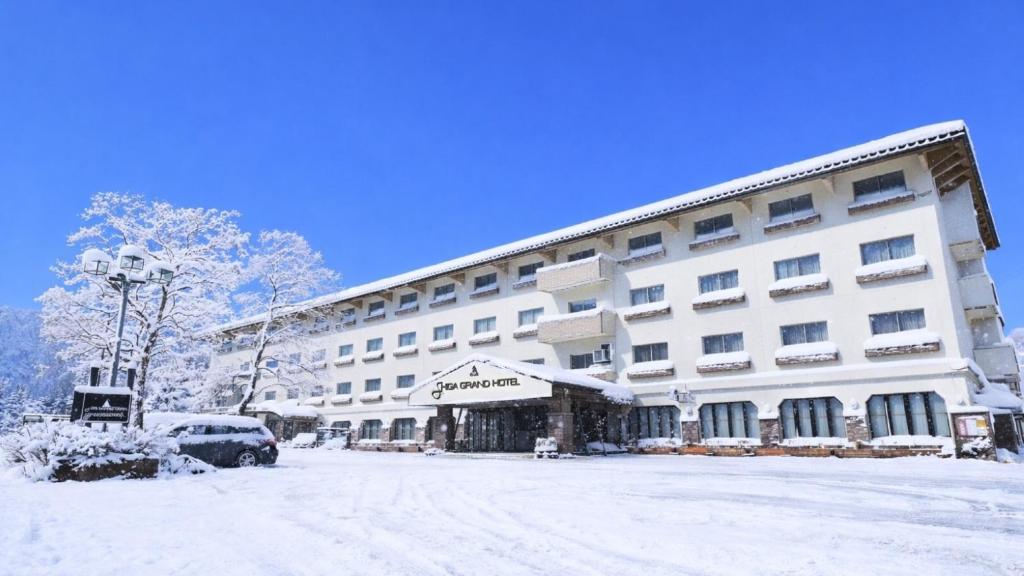 a large white building with snow on the ground at Shiga Grand Hotel in Yamanouchi
