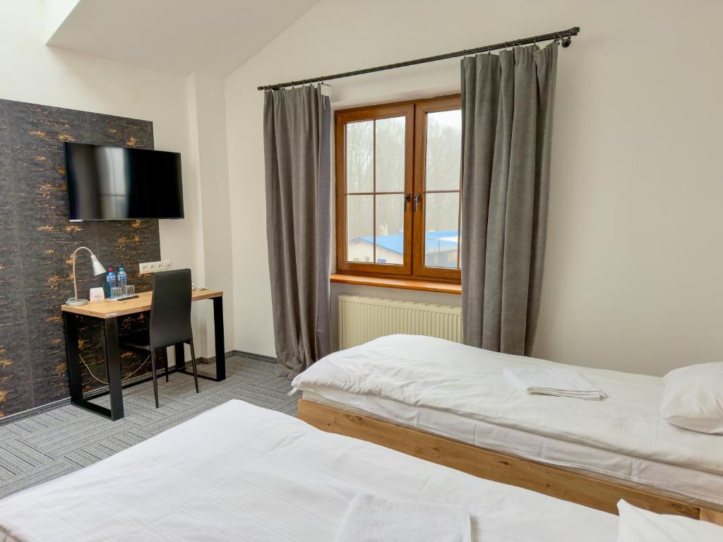 a hotel room with two beds and a desk and a window at Hotel Sjesta in Mikołów