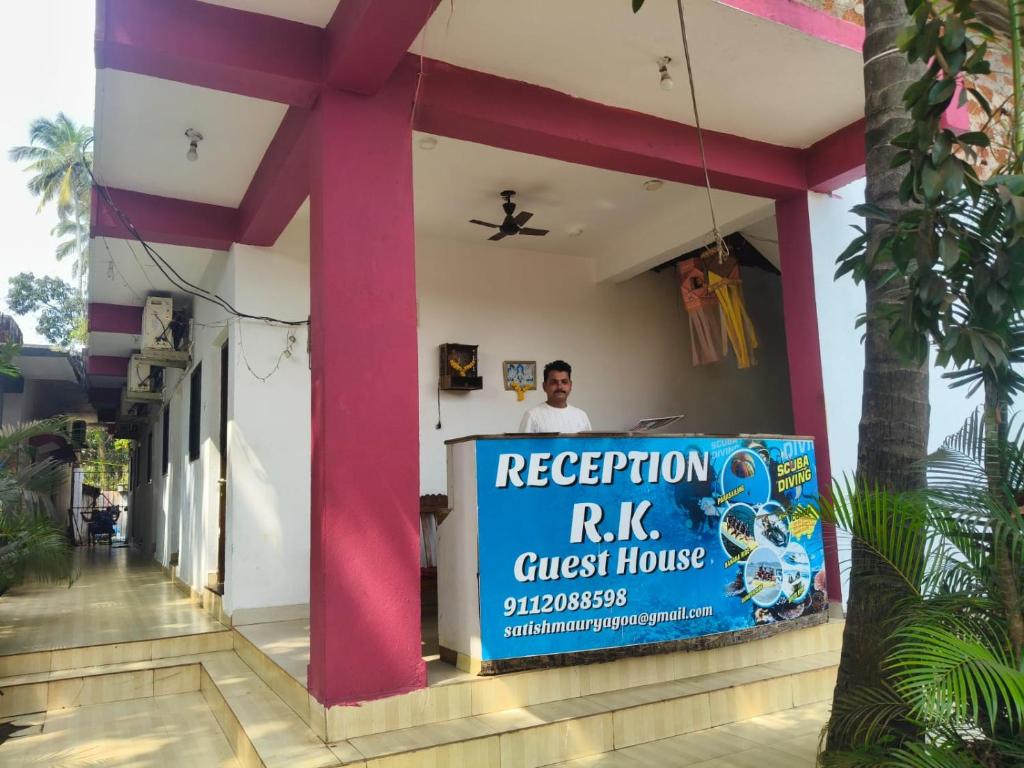 a man standing behind a sign on a building at R K Guest House Arpora in Mapusa