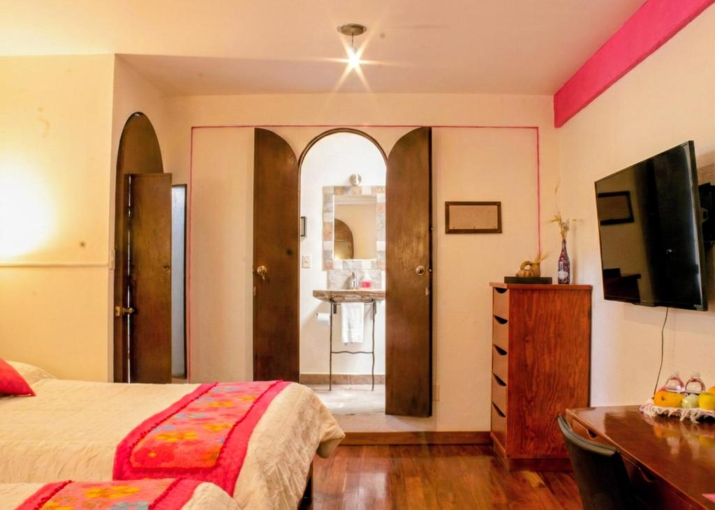a bedroom with a bed and a dresser and a television at Hotel Coyoacan in Mexico City