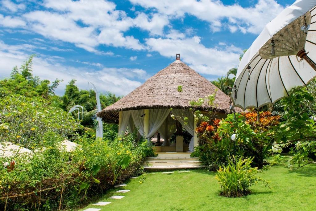 a small hut with a grass roof in a garden at Nomadic Resort Bali in Canggu