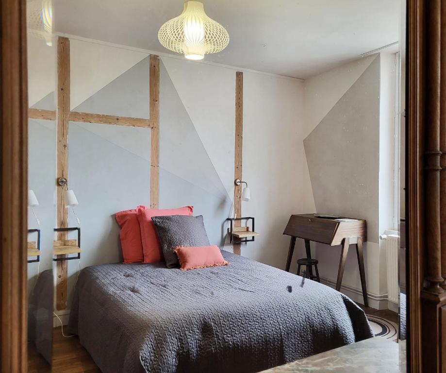 a bedroom with a bed with red pillows and a table at Une nuit à la Clouère in Saint-Maurice-la-Clouère