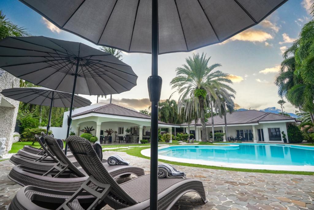 a group of chairs with umbrellas next to a pool at Casa Negrense Private Resort in Dauin