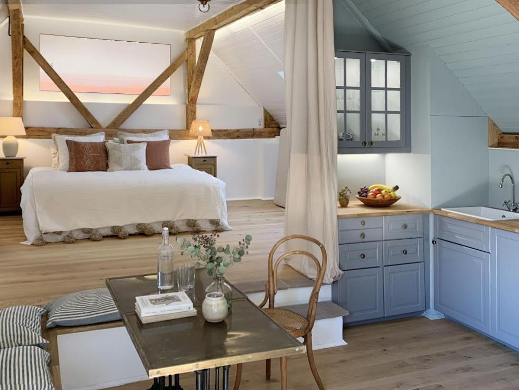 a bedroom with a bed and a table and a kitchen at Appartement cosy au calme avec sauna in Kauffenheim