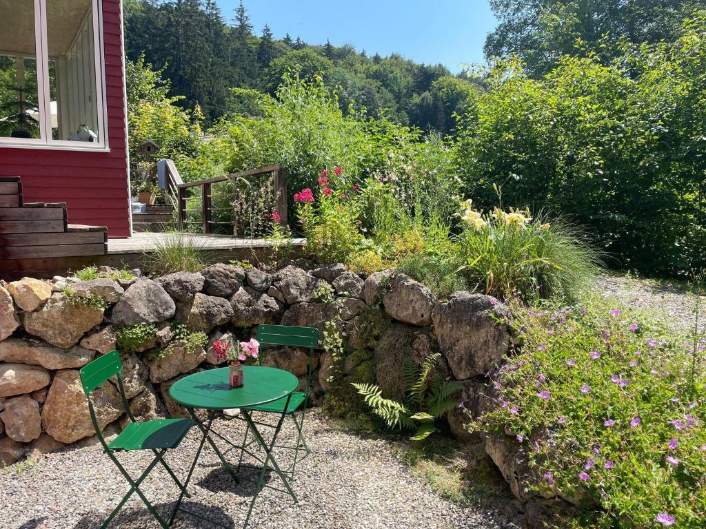 a garden with a table and chairs next to a rock wall at Ferienwohnung am Kienbach in Herrsching am Ammersee