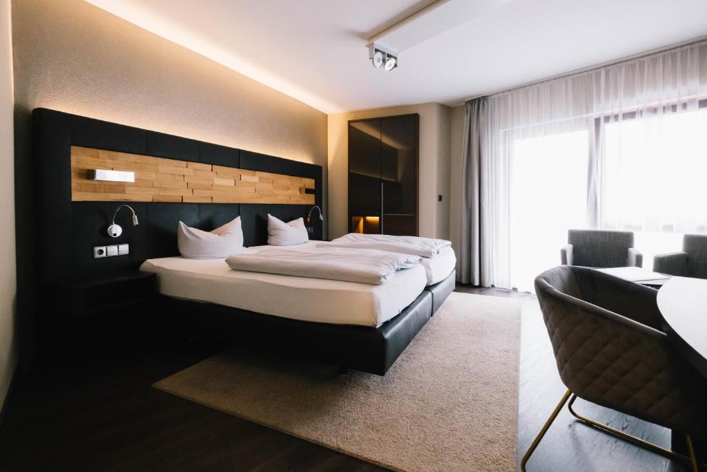 a bedroom with a large bed and a table and chairs at hotel zentlinde in Mossautal