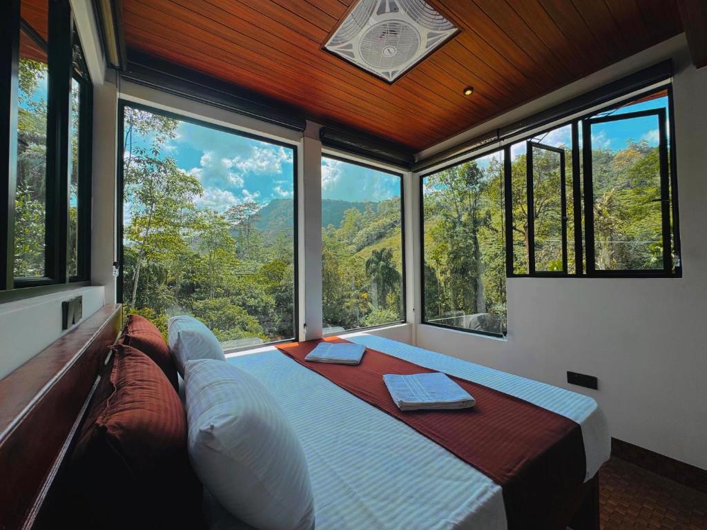 a bedroom with a bed in a room with large windows at Rainforest cabin in Deniyaya