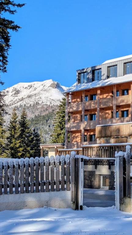 a building with a fence in the snow at Le Rocher Du Cerf in Le Lioran