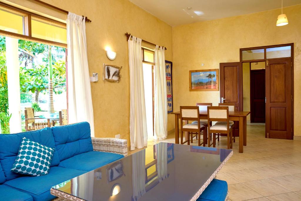 a living room with a blue couch and a table at Flametree Beach Homes in Diani Beach