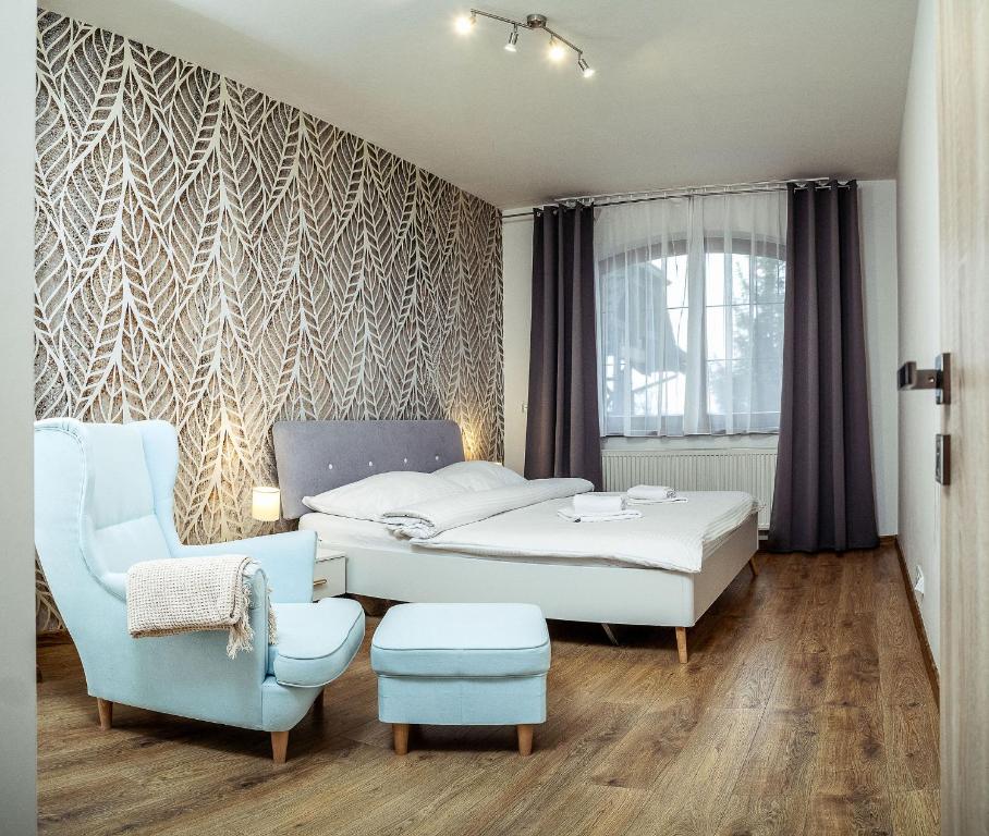 a bedroom with two beds and a chair at Relax & Luxury apartment in Veľká Lomnica