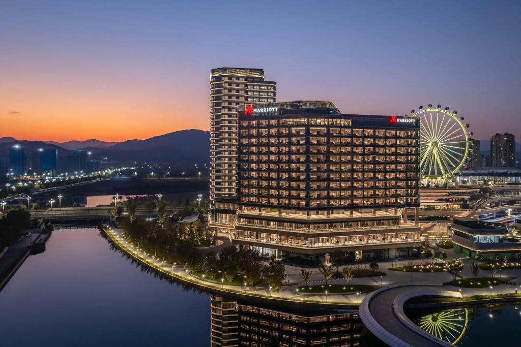 a tall building with a ferris wheel in a city at Deqing Marriott Hotel in Huzhou