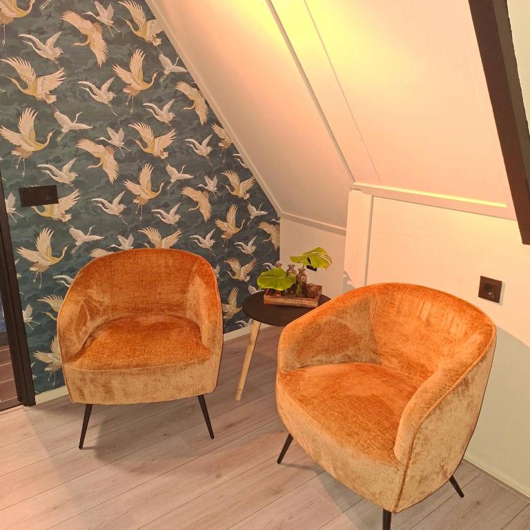 two orange chairs in a room with a wall at B en B de 8 Wieken in Oosterwolde