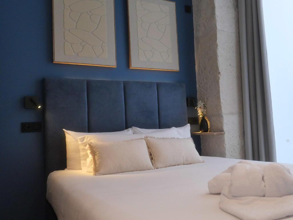 a bed with white pillows and a blue wall at Literal Hostel Madrid in Madrid