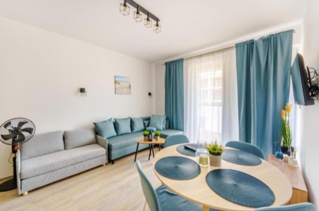a living room with a table and a couch at Perła Bałtyku - kawalerka z dostępem do Resort &MediSpa in Sianozety