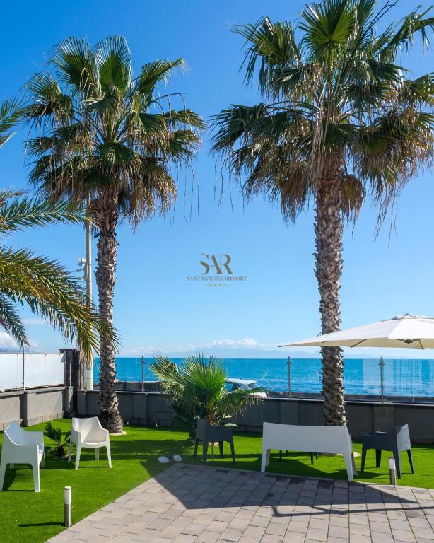 a patio with palm trees and the ocean at Santantonioresort in Riposto