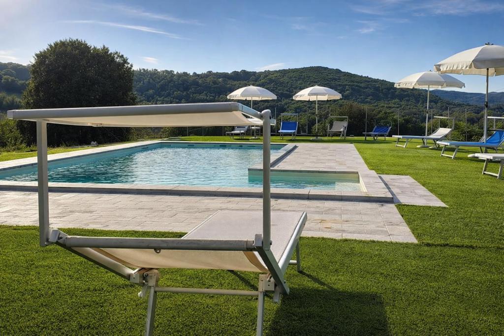 a pool with chairs and umbrellas in a yard at La Casa di Mary in Amelia