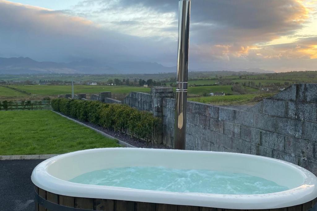 a bath tub sitting on top of a stone wall at Studio Sleeps 2 -Private Hot Tub -Enclosed Garden in Killarney