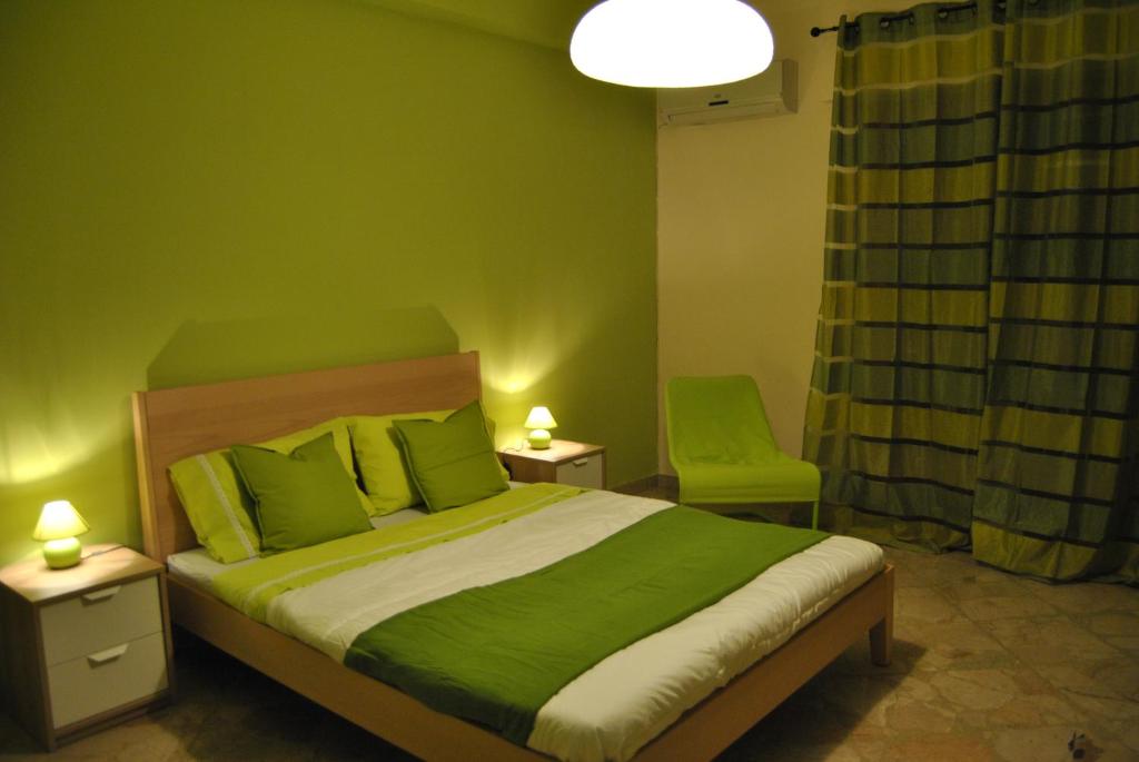 1 dormitorio verde con 1 cama y 1 silla en Magione Apartment&Rooms, en Palermo