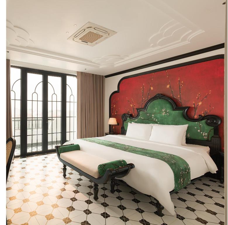 a bedroom with a large bed with a red wall at C'Lau Hotel Ninh Binh - A Gem Nestled in Ancient Quarter in Ninh Binh