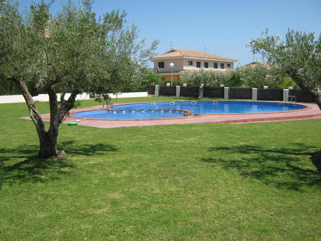 a swimming pool in a yard with a tree at Casa junto a la playa Costa Dorada in L'Ampolla