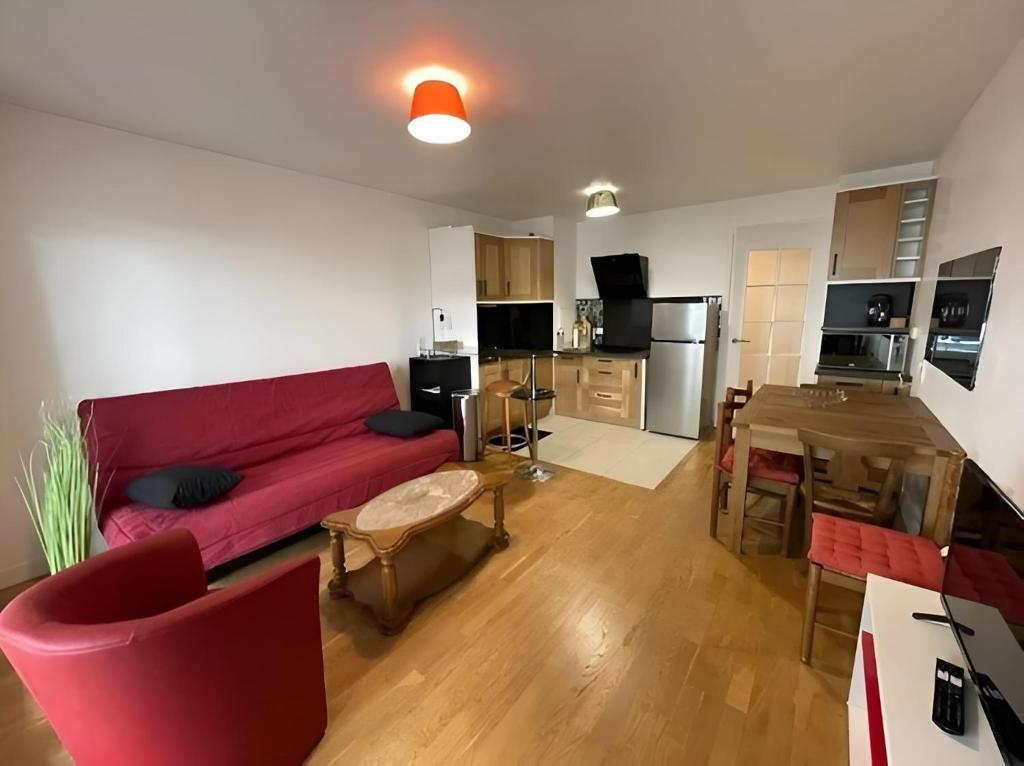 a living room with a red couch and a kitchen at Citronnelle, 2 Chambres, 3 min Métro 8 in Maisons-Alfort