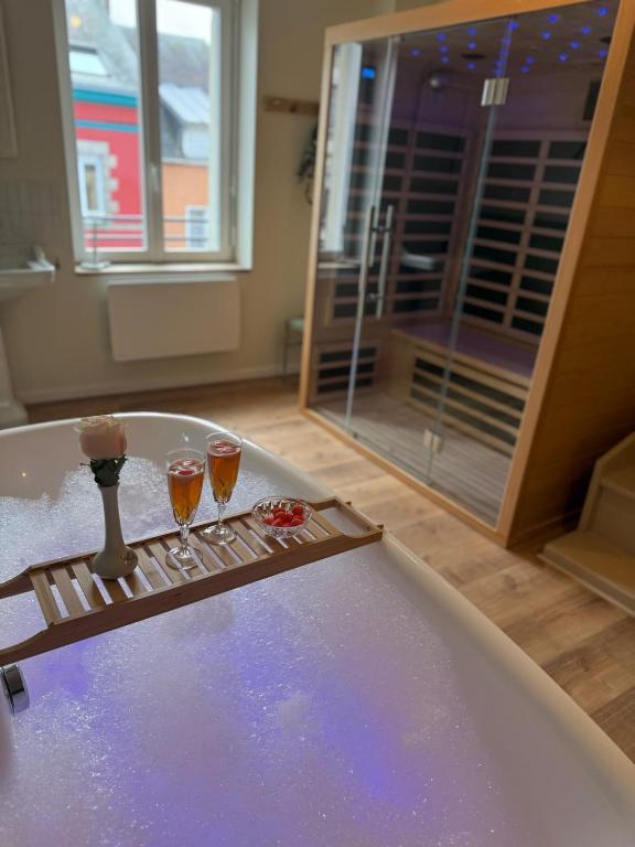 two glasses of wine sitting on a bath tub at L Entre Deux Époques in Pré-en-Pail