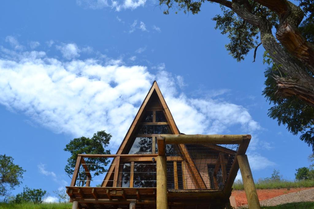 a wooden building with a tree in the background at Chalé Pé da Serra - Região de Monte Verde in Camanducaia