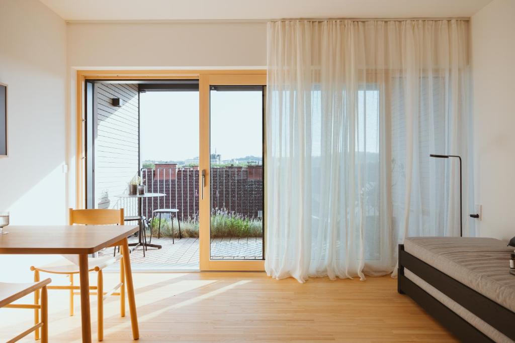 a bedroom with a bed and a table and a sliding glass door at Coho Slowliving in Linz